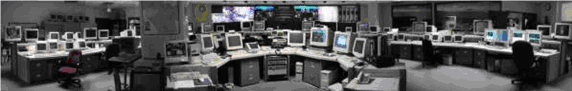 A photo of a TMC control room showing multiple operator consoles and computer workstations.